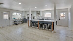 A spacious kitchen with a central island, bar stools, and a dining area with a table and chairs. - Pool, Game Room, Hot Tub: Lake Havasu City Oasis! (Lake Havasu City)