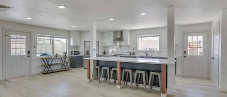 Uma cozinha espaçosa com uma ilha central, banquetas e uma área de refeições com mesa e cadeiras.