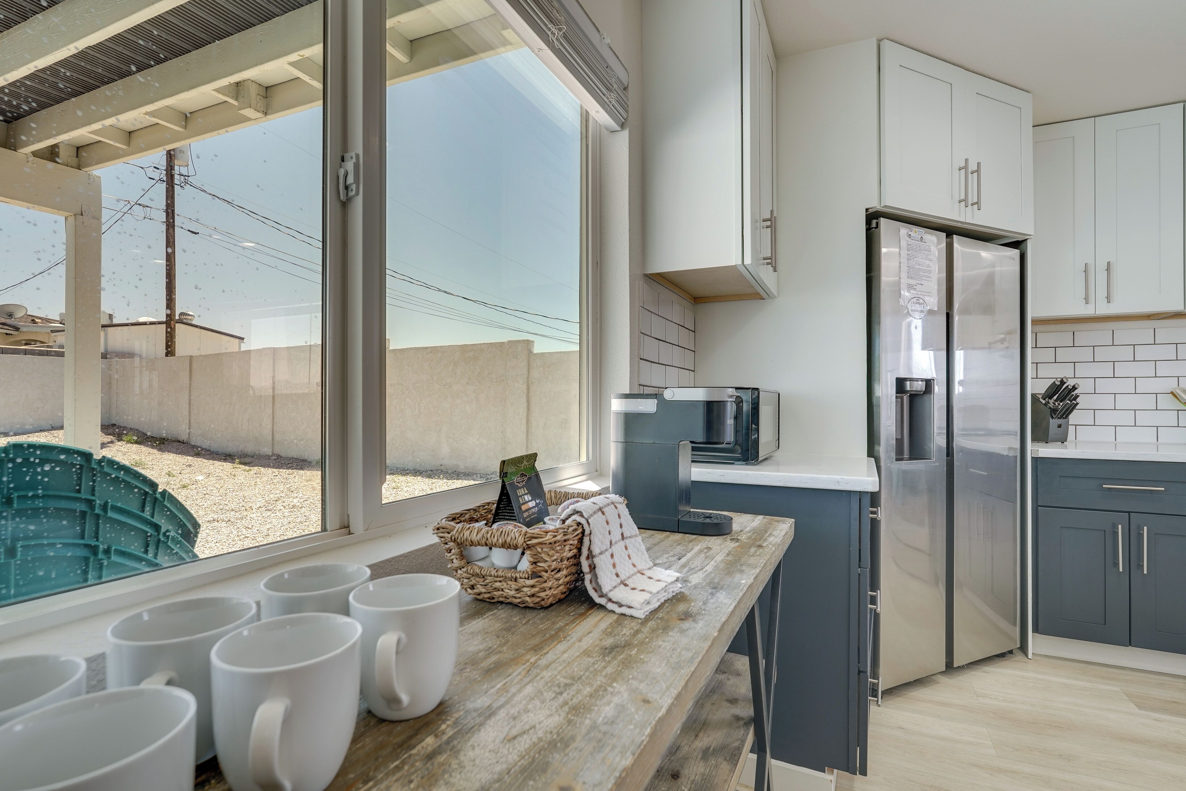 A modern kitchen with a large window, stainless steel appliances, and a wooden countertop.