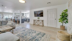 A modern living room with a sofa, coffee table, and a rug. There is a kitchen in the background with cabinets and appliances. - Pool, Game Room, Hot Tub: Lake Havasu City Oasis! (Lake Havasu City)