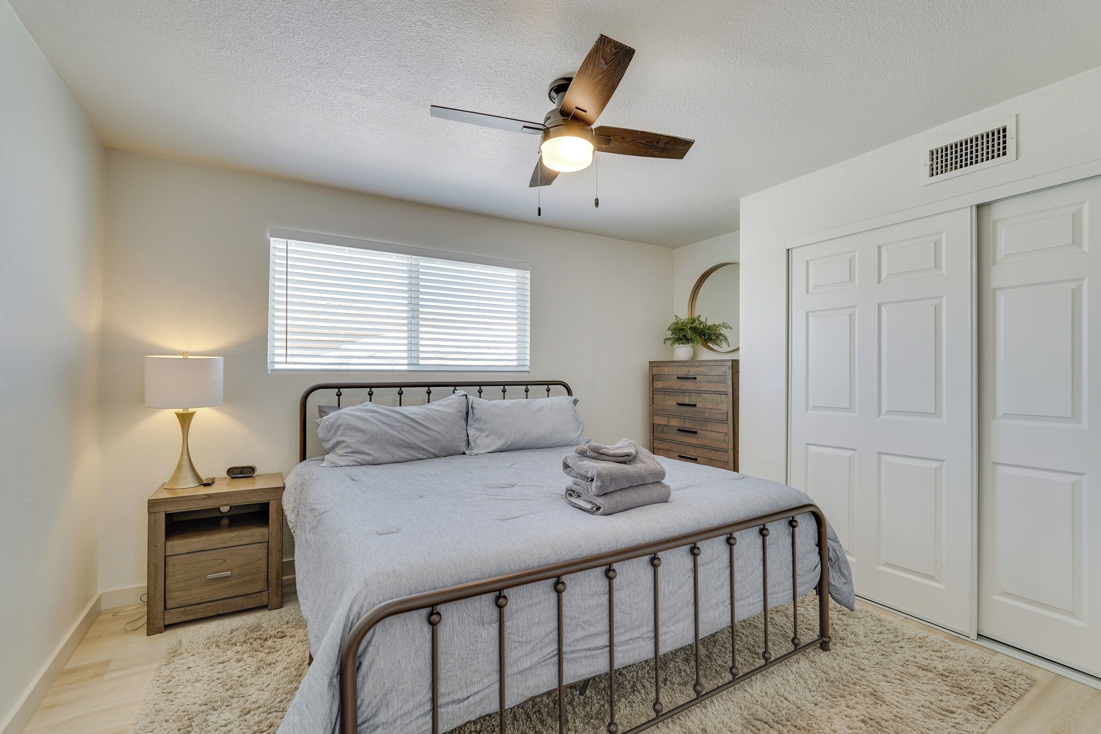 A bedroom with a bed, nightstand, dresser, and a ceiling fan.
