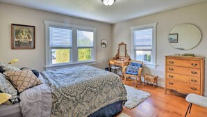A bedroom with a large bed, two windows with blinds, a dresser, a chair, and a desk. - Eureka Cottage Near Sequoia Park & Old Town! (Eureka)