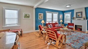 A living room with a red sofa set, wicker chairs, a coffee table, and a fireplace. - Eureka Cottage Near Sequoia Park & Old Town! (Eureka)