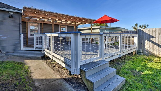 A covered outdoor deck with a red umbrella, a fenced area, and a wooden staircase leading to a house. - Eureka Cottage Near Sequoia Park & Old Town! (Eureka)
