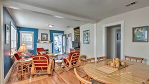 A dining area with a round wooden table, wicker chairs, and a red cushioned bench. - Eureka Cottage Near Sequoia Park & Old Town! (Eureka)