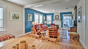 A spacious living room with a large wooden dining table, wicker furniture, and a red sofa set. - Eureka Cottage Near Sequoia Park & Old Town! (Eureka)