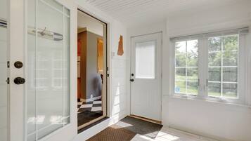 A clean, well-lit entryway with a glass door, a wooden floor, and a window with blinds.