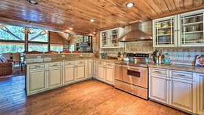 A spacious kitchen with wooden ceiling, stainless steel appliances, and a large island with a built-in oven. - Fish Creek Ranch Lodge With Hot Tub and Game Room (Dolores)