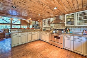 A spacious kitchen with wooden ceiling, stainless steel appliances, and a large island with a built-in oven. - Fish Creek Ranch Lodge With Hot Tub and Game Room (Dolores)