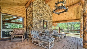 A wooden deck with wicker furniture and a stone wall. - Fish Creek Ranch Lodge With Hot Tub and Game Room (Dolores)