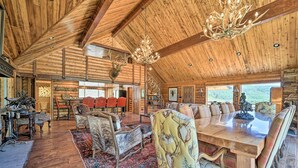 A spacious log cabin interior with a large dining table, multiple chairs, a fireplace, and a chandelier. - Fish Creek Ranch Lodge With Hot Tub and Game Room (Dolores)