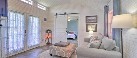 A spacious living room with a large window, a ceiling fan, a sofa, and a rug.