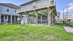 A two-story building with a balcony, a covered porch, and a grassy yard. - Walk to Ocean: Bright Crystal Beach House w/ Deck! (Port Bolivar)