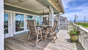 A wooden deck with outdoor furniture, a potted plant, and a view of the ocean. - Walk to Ocean: Bright Crystal Beach House w/ Deck! (Port Bolivar)