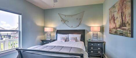 A bedroom with a bed, two bedside tables, a ceiling fan, a hammock, and a painting on the wall.