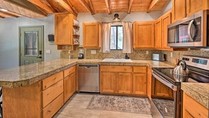 A kitchen with wooden cabinets, granite countertops, a stainless steel dishwasher, a microwave, and a stove. - Cabin in Tonto National Forest: Deck & Views! (Pine)