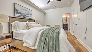 Un dormitorio con una cama, mesitas de noche, un ventilador de techo y un cuadro en la pared.