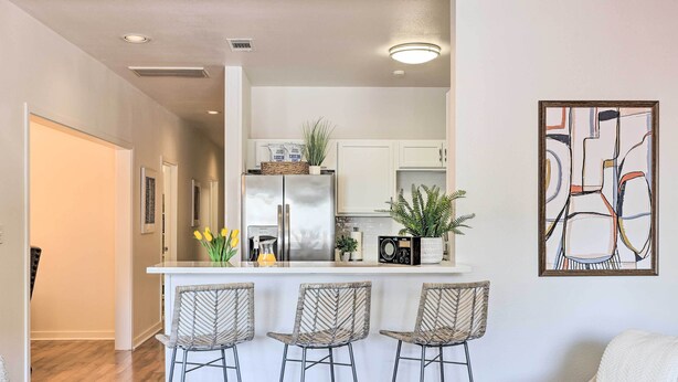 Una cocina moderna con una isla central, taburetes de bar y un comedor.