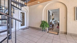 Vestíbulo de hotel con piso de baldosas, una escalera, mostrador de recepción y una planta en maceta.