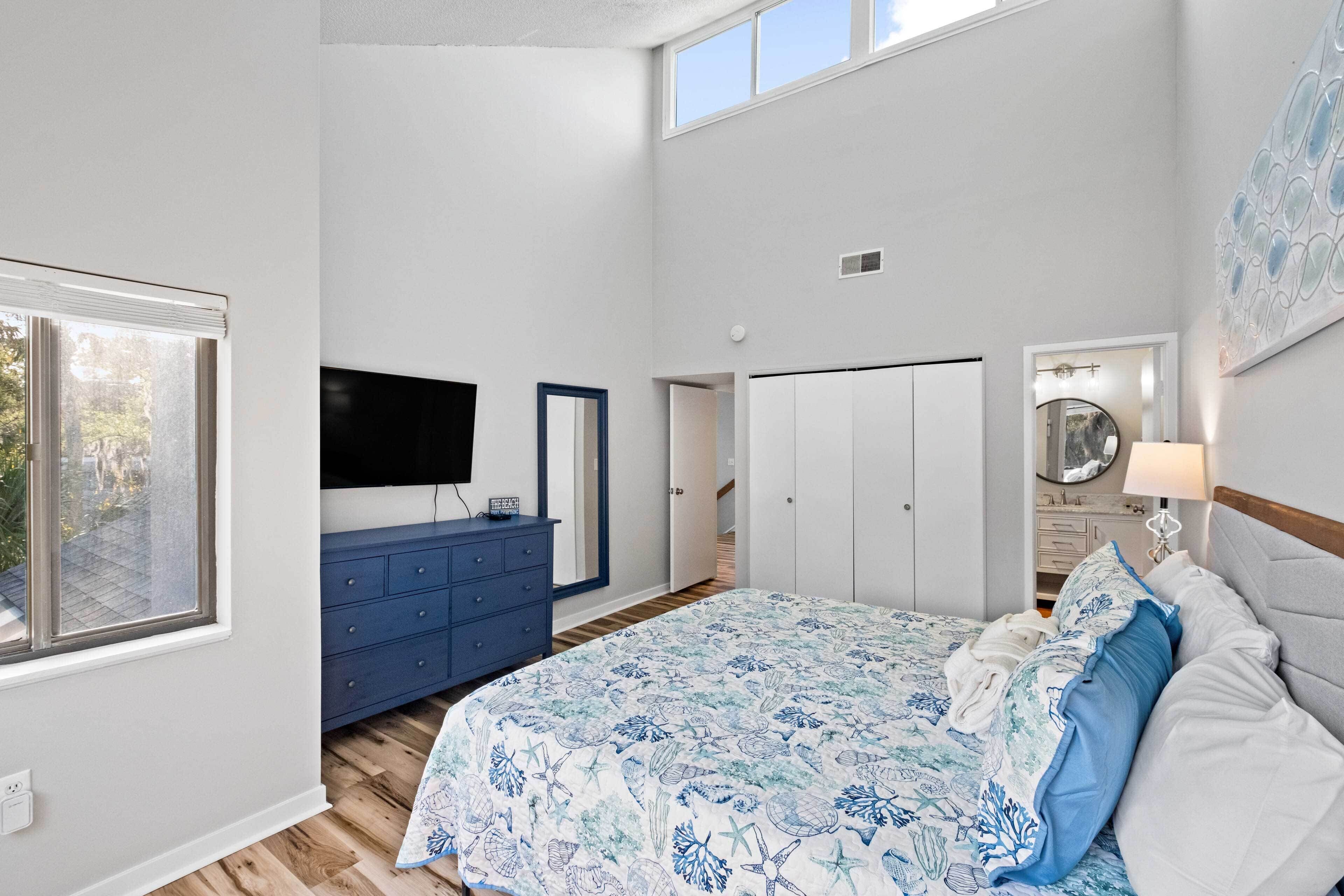 A bedroom with a bed, dresser, TV, wardrobe, and a window.