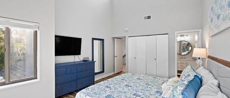 A bedroom with a bed, dresser, TV, wardrobe, and a window.