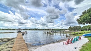 A wooden dock leading to a sandy beach with colorful chairs and a covered area. - Florida Family Home w/ Dock on Saw Mill Lake! (Clermont)