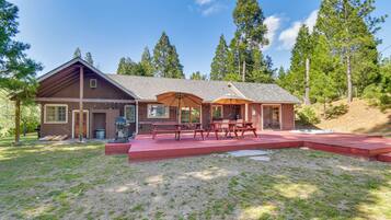 A cabin with a covered patio, picnic tables, and a fire pit.