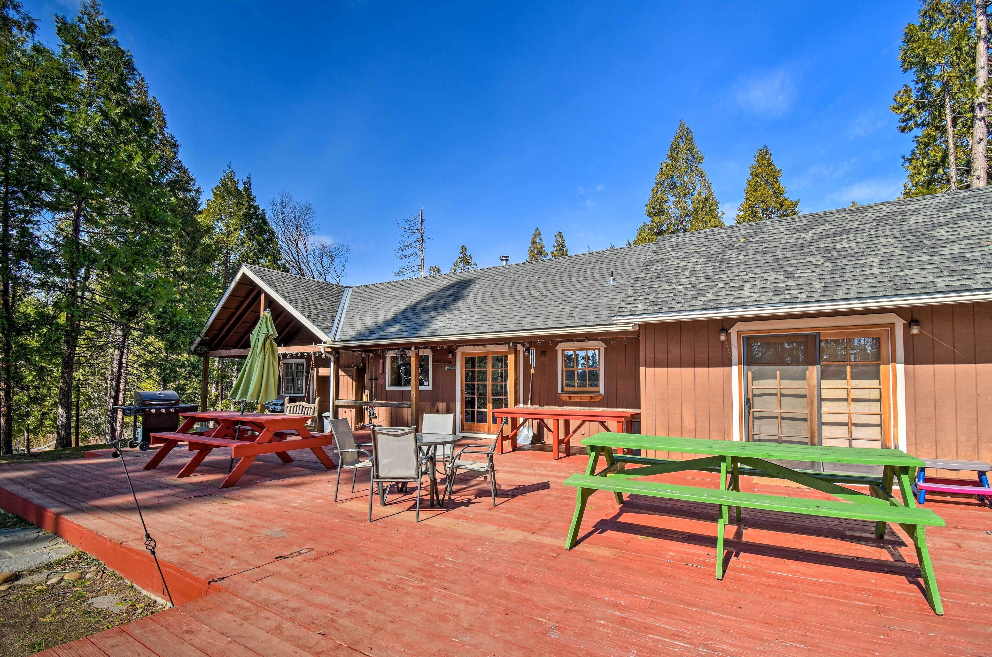 A lodge with a covered patio area, picnic tables, and a grill.