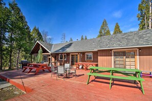 Eine Lodge mit überdachter Terrasse, Picknicktischen und Grill.