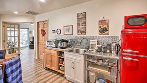 A modern kitchen with a red refrigerator, stainless steel appliances, and a tiled backsplash.