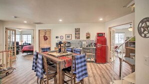 A spacious kitchen with wooden flooring, a dining area with a table set for four, and a red refrigerator.