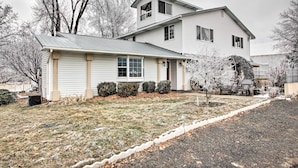 A two-story house with a front porch, a garage, and a small front yard with a lawn and a gravel path.