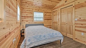 A wooden-paneled bedroom with a bed, a nightstand, and a window.