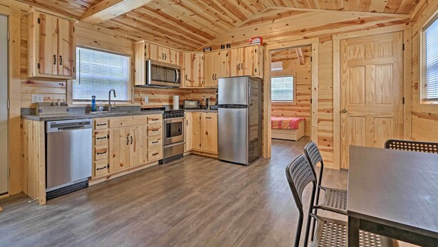 A wooden cabin-style kitchen with a central island, stainless steel appliances, and a dining area with a table and chairs.