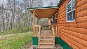 A wooden cabin with a wooden porch and a green railing.