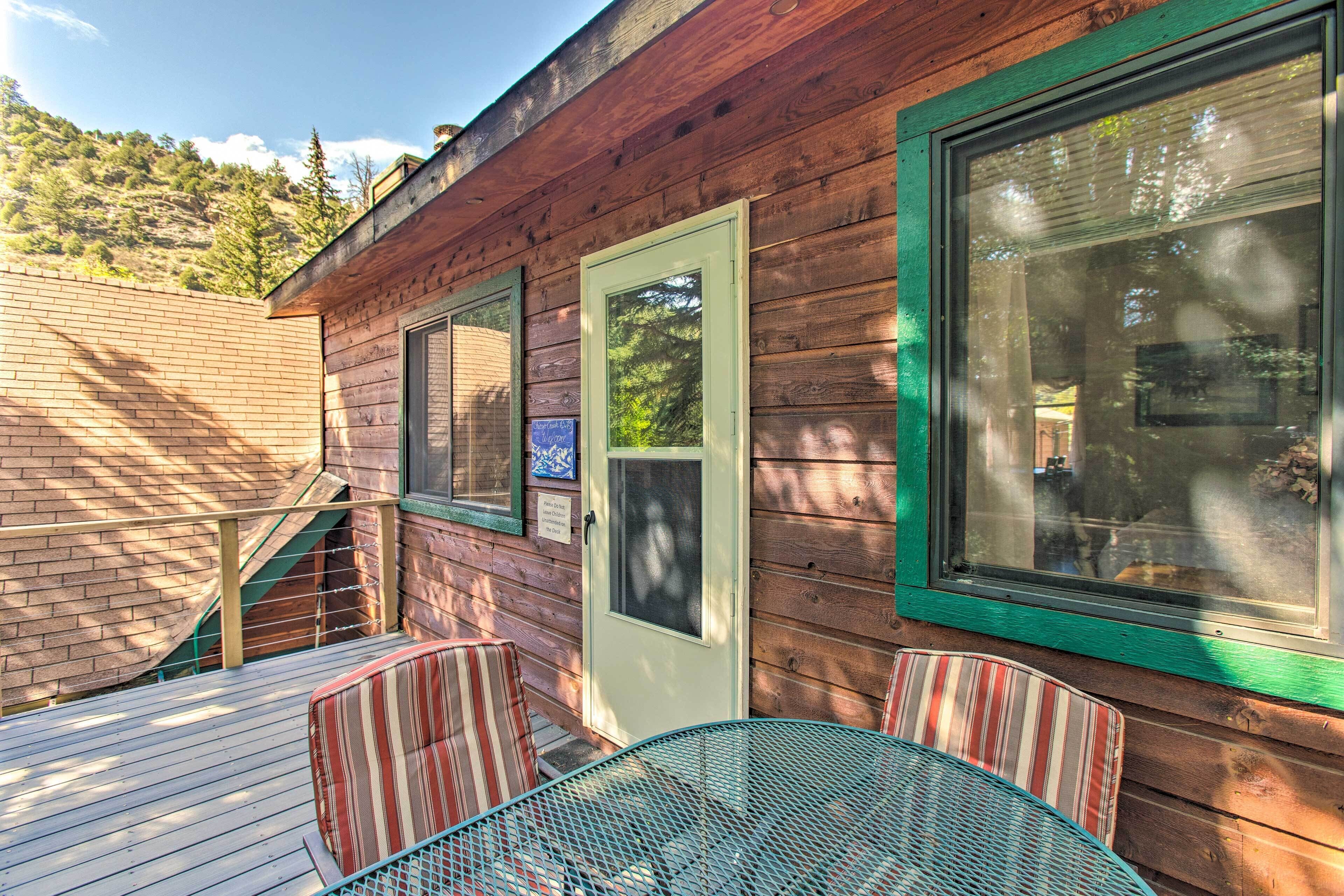 Une cabane en bois avec une terrasse, une porte et une fenêtre.