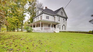 A large, two-story house with a front porch and a well-maintained lawn. - Historic Victorian Farmhouse w/ Porch & Views! (Mayville)