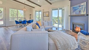 A spacious living room with a sectional sofa, a fireplace, and a balcony with a view. - Mtn Views & Gas Fire Pit: Luxe Pine Escape! (Pine)