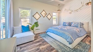 A bedroom with a bed, a sofa, a ceiling fan, and a large window. - Mtn Views & Gas Fire Pit: Luxe Pine Escape! (Pine)