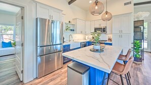 A modern kitchen with stainless steel appliances, white cabinets, and a marble island with bar stools. - Mtn Views & Gas Fire Pit: Luxe Pine Escape! (Pine)