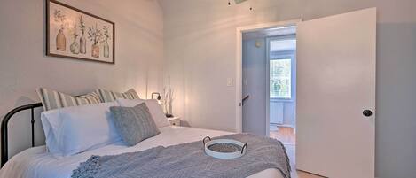 Un dormitorio con una cama, un ventilador de techo, una obra de arte enmarcada y una puerta que da a un balcón.