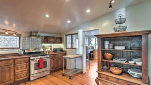 A kitchen with wooden cabinets, stainless steel appliances, and a wooden shelf unit. - Victorian Gem! Steps to Dine, Shop & Hike (Carbondale)