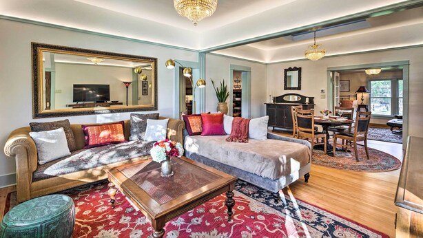 A spacious living room with a large sofa, a coffee table, and a dining area with a chandelier. - Victorian Gem! Steps to Dine, Shop & Hike (Carbondale)