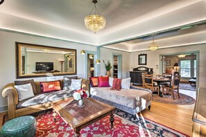A spacious living room with a large sofa, a coffee table, and a dining area with a chandelier. - Victorian Gem! Steps to Dine, Shop & Hike (Carbondale)