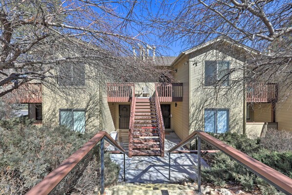 A staircase leading to a building with a metal railing, surrounded by shrubs and trees. - Flagstaff Condo < 1 Mi to Golfing & Hiking! (Flagstaff)