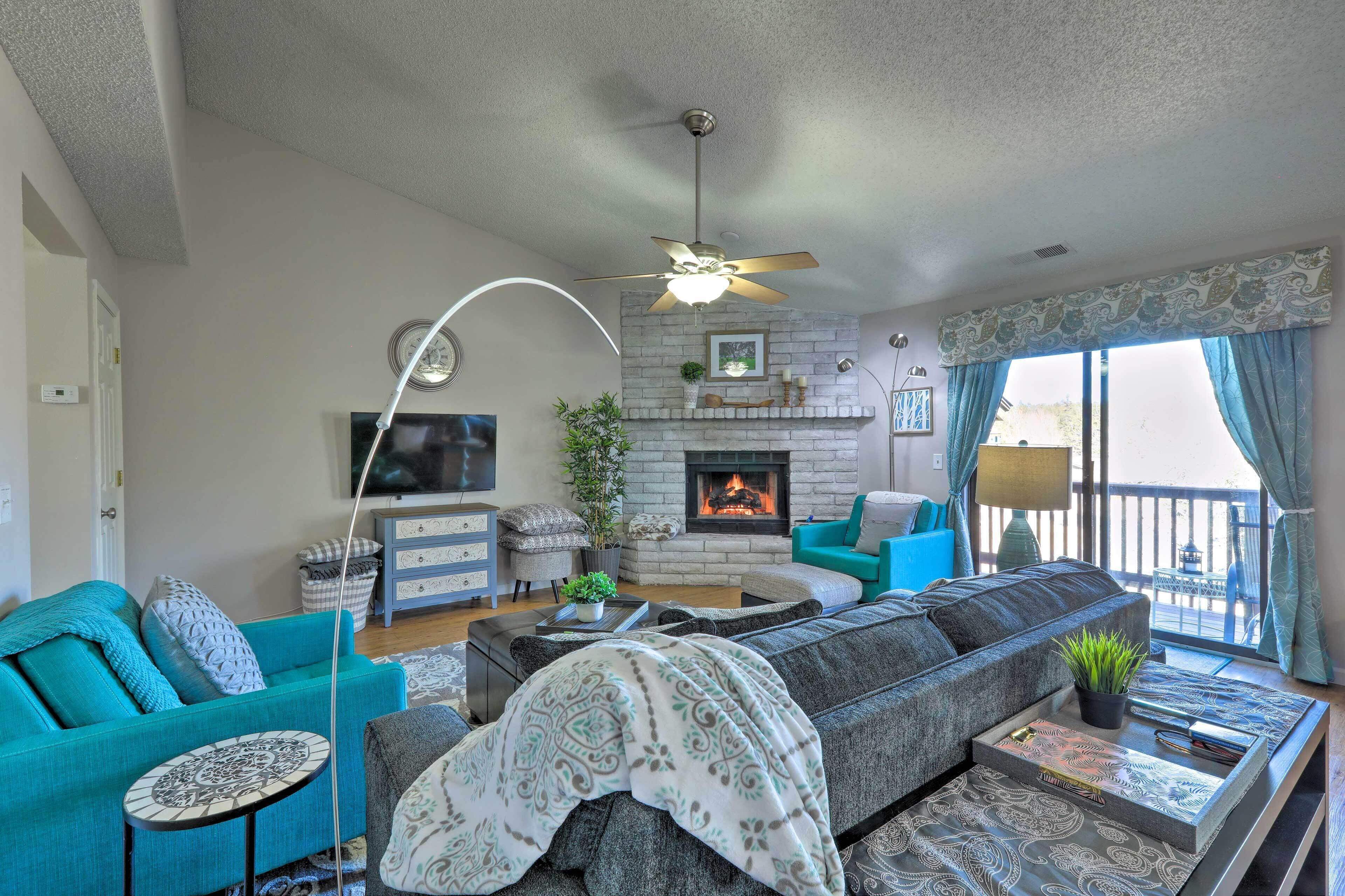 A living room with a fireplace, sofa, and a balcony with curtains.
