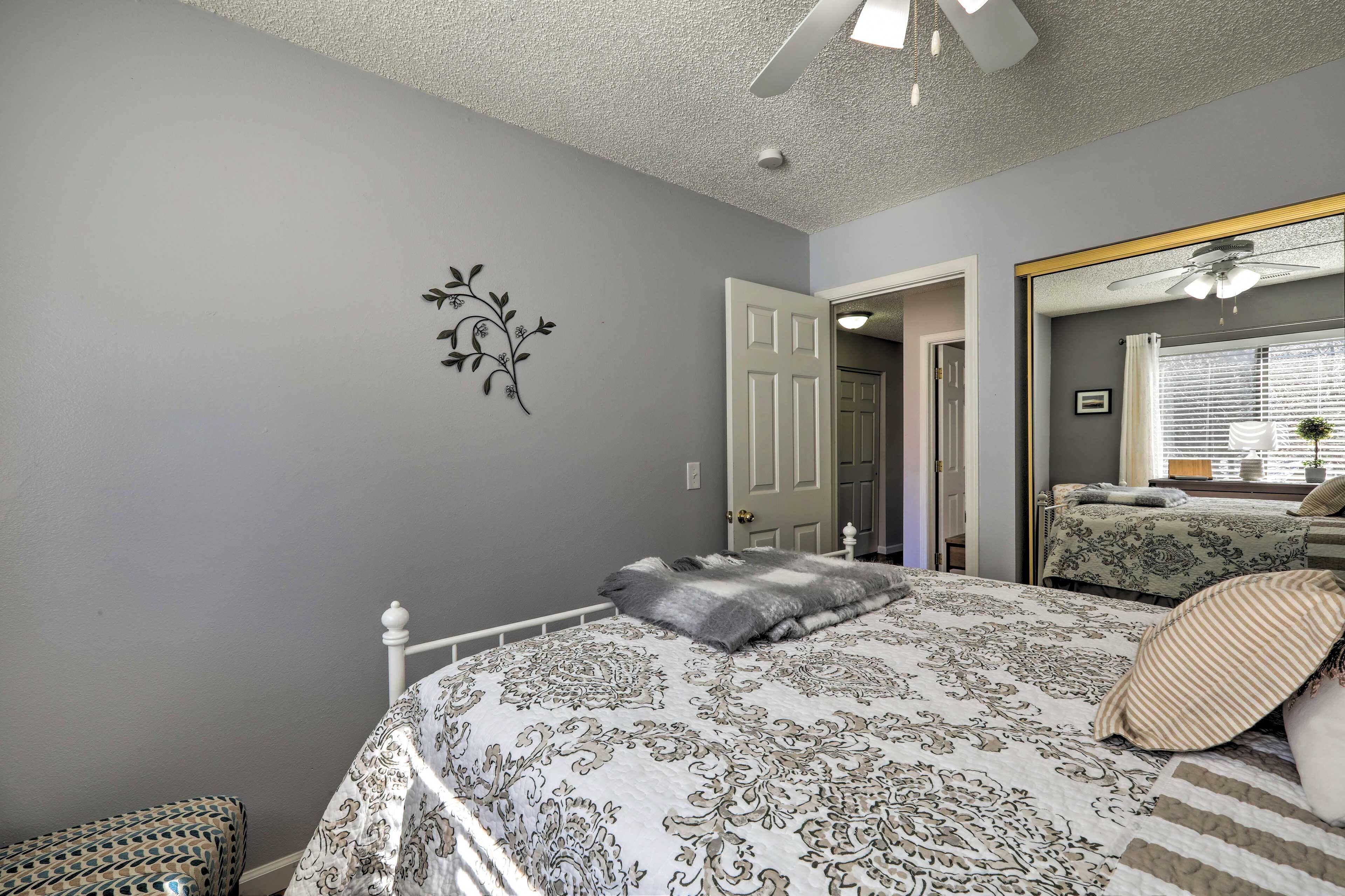 Une chambre à coucher avec un lit, un ventilateur de plafond, une porte et un miroir.