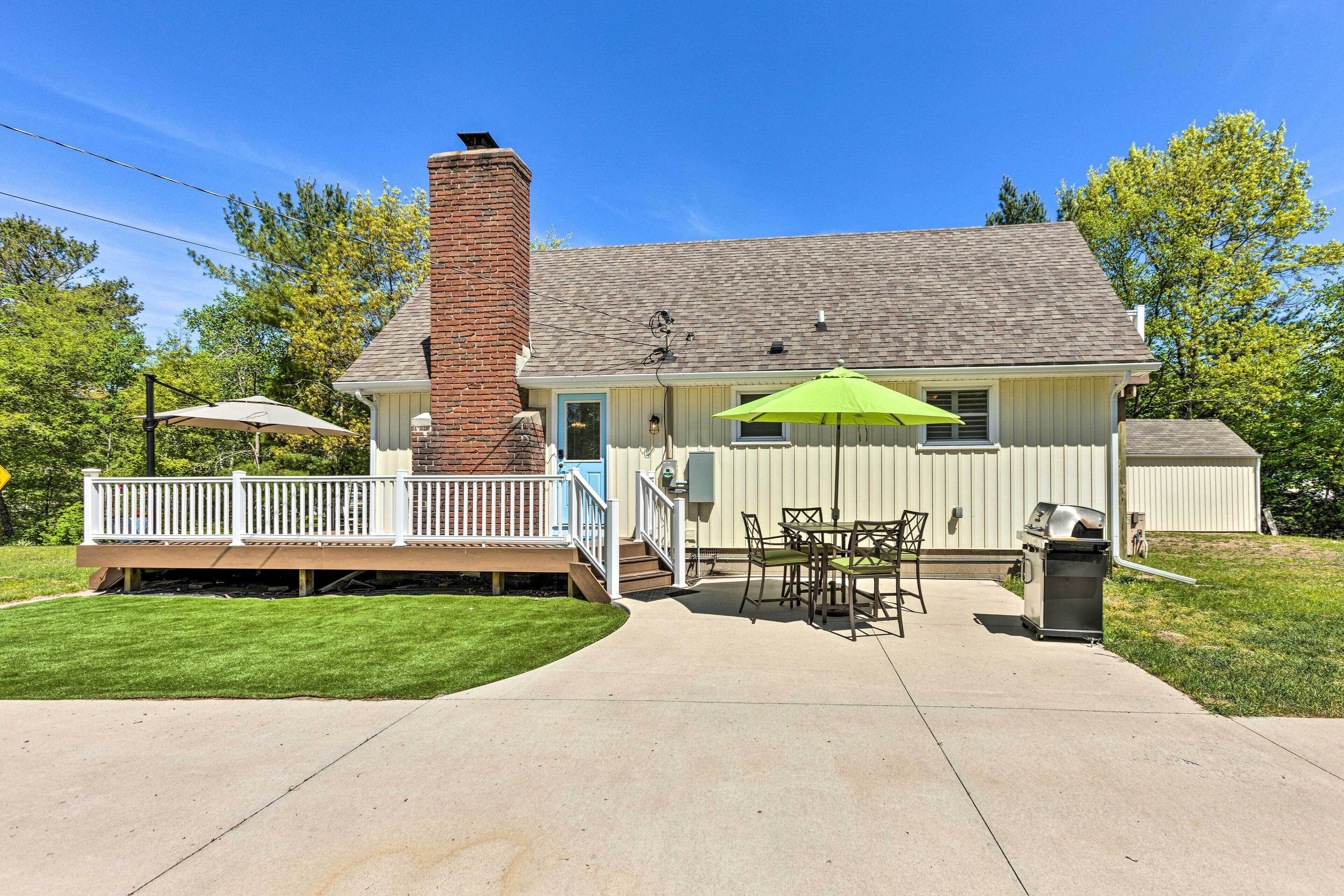 Ein Haus mit überdachter Terrasse, Schornstein, umzäunter Deck und Grill.