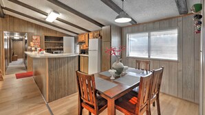 Une cuisine moderne avec des meubles en bois, un îlot central et un coin repas comprenant une table et des chaises en bois.