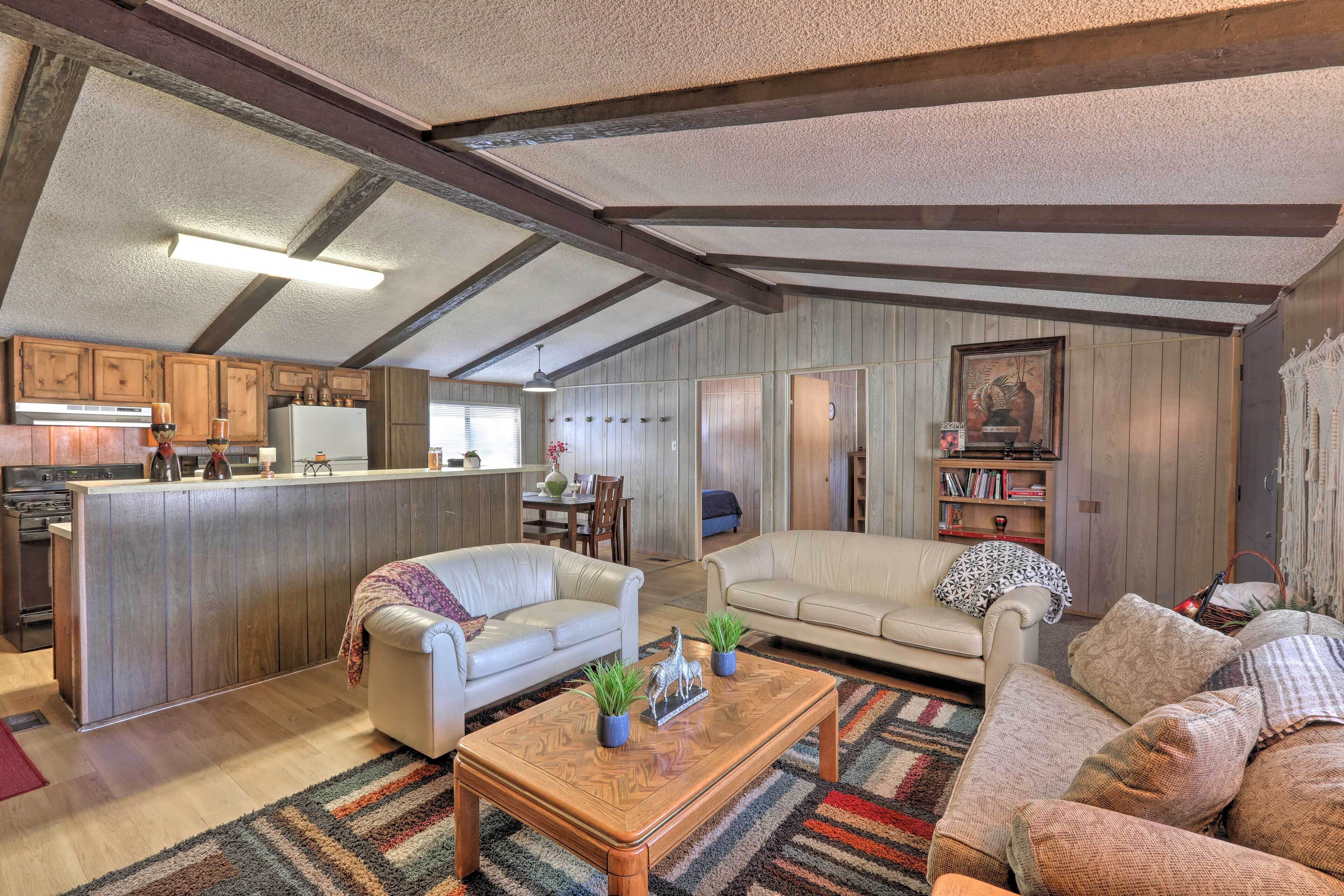 A spacious living area with a kitchen, two sofas, a coffee table, and a dining table.